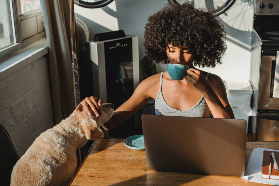 kobieta-przy-laptopie-pije-kawe-i-glaszcze-psa
