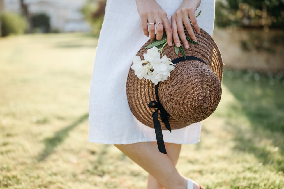 kobieta-w-bialej-sukience-trzyma-kapelusz-slomkowy-i-kwiaty