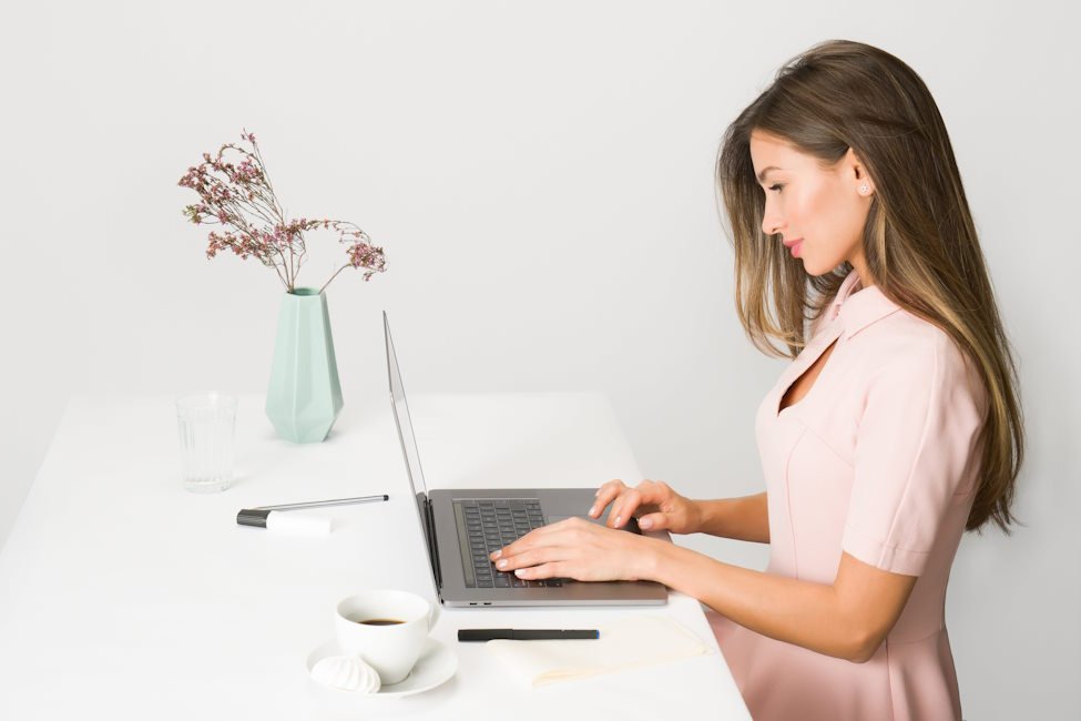 kobieta-w-rozowej-sukience-pracuje-na-laptopie-przy-bialym-stole